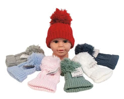 A collection of knit pom-pom beanies in multiple colors including red, gray, light blue, pink, sage green, white, and navy, displayed on a mannequin head against a white background.